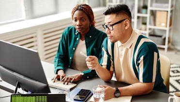 man and woman looking at computer