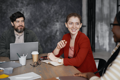 a woman in red talking to 2 people at a table with coffee