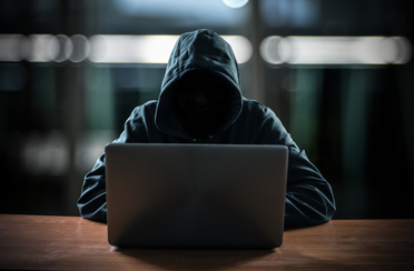 hacker in hoodie by computer