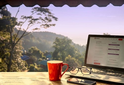 Medius savings calculator on laptop screen in a mountain setting