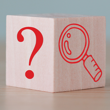 wood block with question mark and magnifying glass printed on two sides