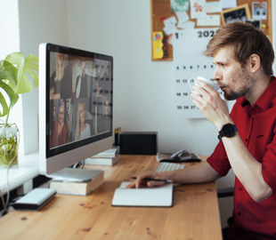 man drinking coffee during online meeting
