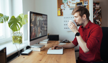 man drinking coffee during online meeting