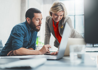 man and woman looking focused at computer screen