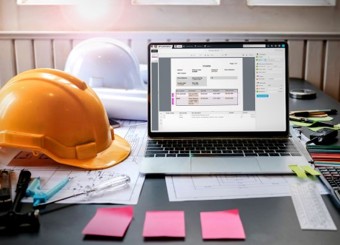 Yellow Construction hat on a table next to an open laptop