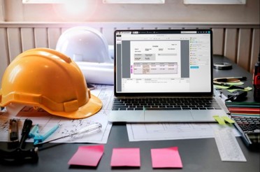 Yellow Construction hat on a table next to an open laptop