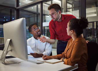 two men and a woman working late by computer
