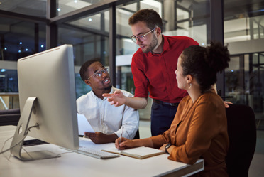 two men and a woman working late by computer