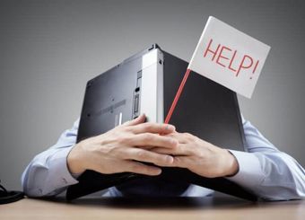 Person holding laptop to their face with a "Help!" sign