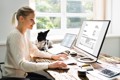 woman at home sitting at a desk smiling at a computer